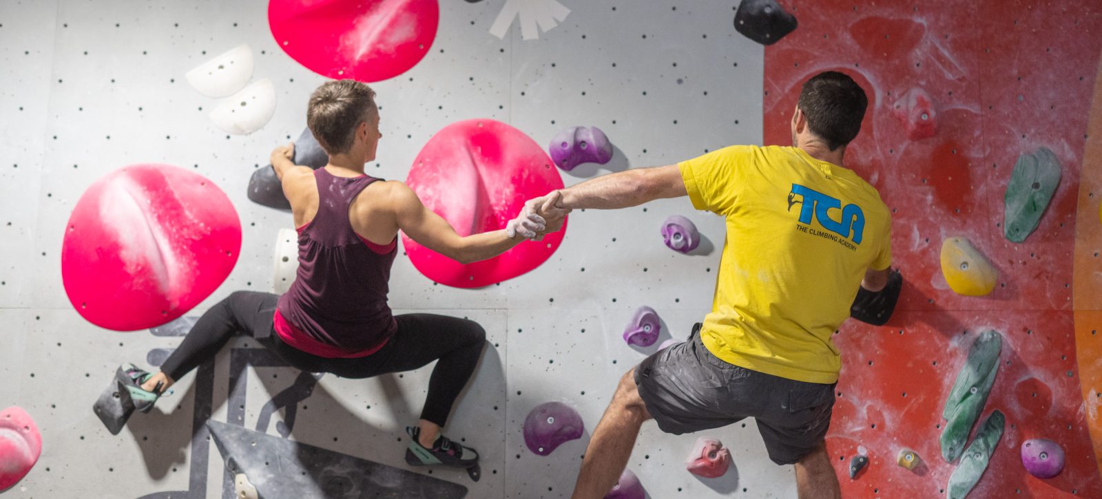 Couple holding hands climbing together on a climbing wall during an active date night in Glasgow.