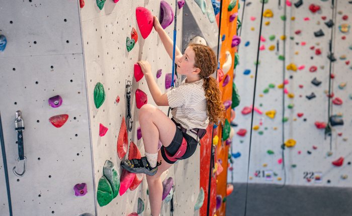 Girl climbing on an indoor climbing wall during summer holiday session